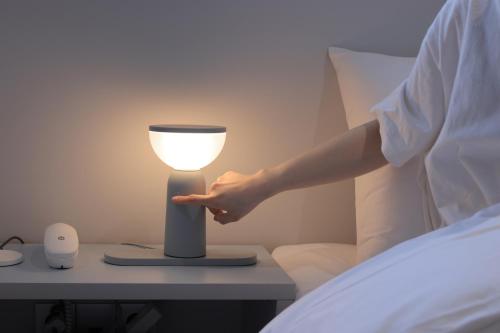 a person reaching for a light on a table next to a bed at Aank Air Hotel Daejeon in Geochang