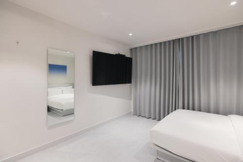 a white bedroom with a bed and a mirror at Aank Air Hotel Daejeon in Geochang