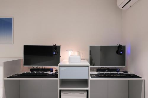 two computer monitors sitting on top of a desk at Aank Air Hotel Daejeon in Geochang