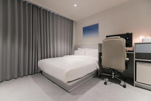 a bedroom with a bed and a desk and a chair at Aank Air Hotel Daejeon in Geochang