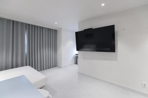 a white room with a flat screen tv on a wall at Aank Air Hotel Daejeon in Geochang
