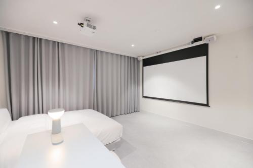 a room with two beds and a projection screen at Aank Air Hotel Daejeon in Geochang