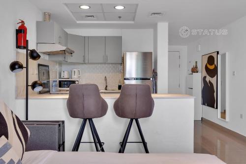 een keuken met twee stoelen voor een aanrecht bij Sleek Studio - Red Residence-L8 - Near ISD Stadium in Dubai