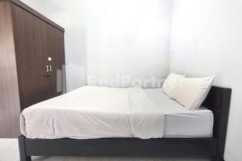 a bed with white sheets and pillows in a room at Vins Homestay Kroya Mitra RedDoorz in Cilacap