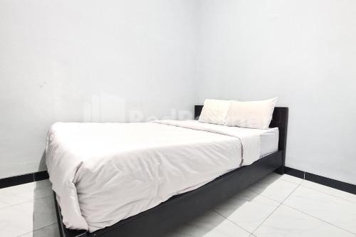 a white bed with white sheets and pillows on it at Vins Homestay Kroya Mitra RedDoorz in Cilacap