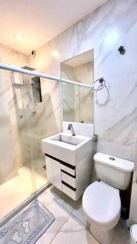 a white bathroom with a toilet and a sink at Loft Sofisticado Rua Sete in Vitória