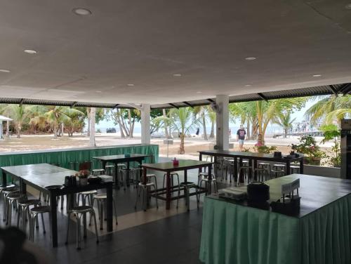 un restaurant avec des tables, des chaises et des palmiers dans l'établissement Pom-Pom Celebes Beach Resort邦邦岛西里伯斯度假村, à Semporna