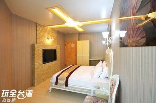 1 dormitorio con 1 cama y ventilador de techo en 自由塔精品民宿, en Magong