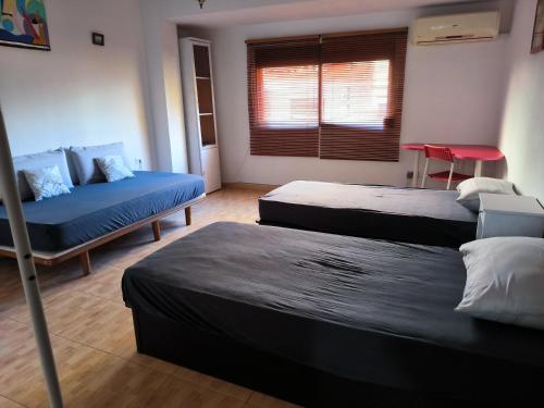 une chambre avec trois lits et un canapé et une fenêtre dans l'établissement Valencia, à Valence