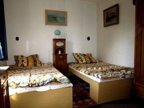 2 Betten in einem Zimmer mit einer Uhr an der Wand in der Unterkunft Beide Ferienwohnungen befinden sich direkt am kleinen Bergsee mit Blick auf den Wald in Mariánská