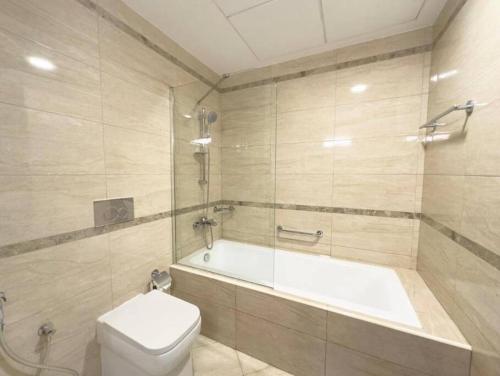 a bathroom with a tub and a toilet and a sink at Cozy Villa with Pool Access in Ras al Khaimah