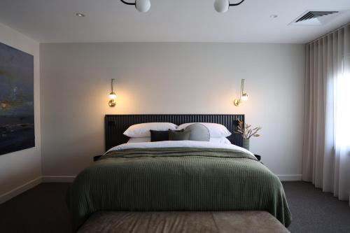 a bedroom with a bed with a green blanket at The Waggon Stables Boutique Accommodation in Hobart