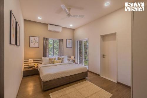een slaapkamer met een bed en een raam bij StayVista's Silver Grove - Serene Haven with Expansive Lawn & Terrace in Nashik