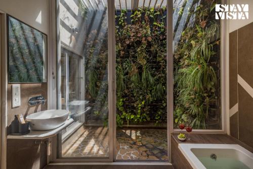 een badkamer met een bad en een raam met planten bij StayVista's Silver Grove - Serene Haven with Expansive Lawn & Terrace in Nashik