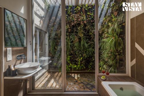 a bathroom with a tub and a window with plants at StayVista's Silver Grove - Serene Haven with Expansive Lawn & Terrace in Nashik