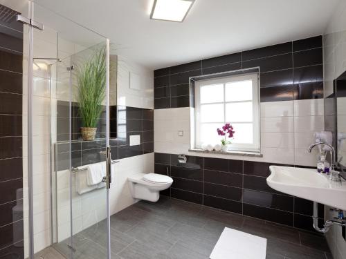a bathroom with a toilet and a sink and a window at Central City Hotel in Füssen