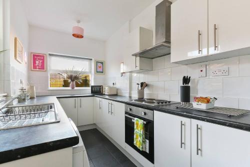 a white kitchen with white cabinets and a sink at 5 Beds Sleeps 8 Contractor House Permit Park in Nottingham
