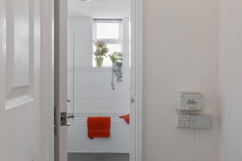 łazienka z pomarańczowym ręcznikiem i oknem w obiekcie Perfect Retreat 4bed House Trent Bridge & Forest w Nottingham