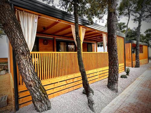 a wooden house with trees in front of it at Mobile home TASHA in Biograd na Moru