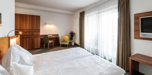 a hotel room with a white bed and a desk at Hotel Clara in Bressanone