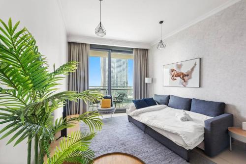 a living room with a blue couch and a plant at FIRST CLASS 1BR Beautifully Furnished in Dubai