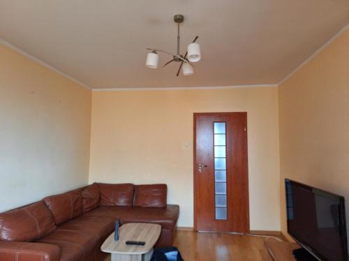 un salon avec un canapé en cuir brun et une télévision dans l'établissement Apartament Stalowa Wola centrum, à Stalowa Wola