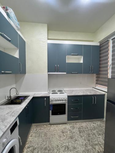 a kitchen with blue cabinets and a stove top oven at Dom Shohon in Dushanbe