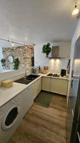 une cuisine avec un évier et une machine à laver dans l'établissement Maison de famille, à Vallecalle