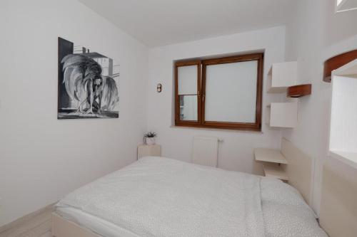 - une chambre blanche avec un lit et une fenêtre dans l'établissement Apartament Słoneczny 10, à Carolinensiel