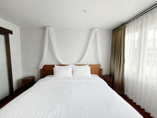 1 dormitorio con 1 cama blanca grande con almohadas blancas en Homie Non - โฮมมี่ นนท์, en Ban Bang Khwang