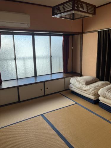a room with two beds and two windows at 尾道ゲストハウス シータ村 in Onomichi