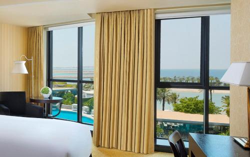 um quarto de hotel com uma cama, uma secretária e uma grande janela em The Ritz-Carlton, Bahrain em Manama
