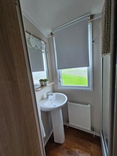 uma casa de banho com um lavatório branco e uma janela em 107 Arran View with WiFi em Ayr