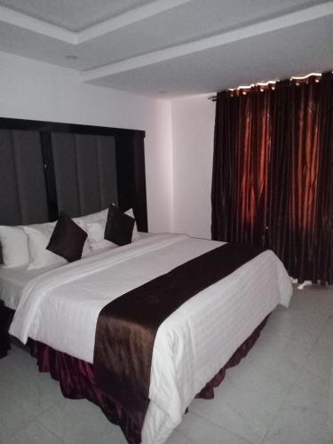 een slaapkamer met een groot wit bed en zwarte gordijnen bij Jada Lifestyle & Lounge in Lagos