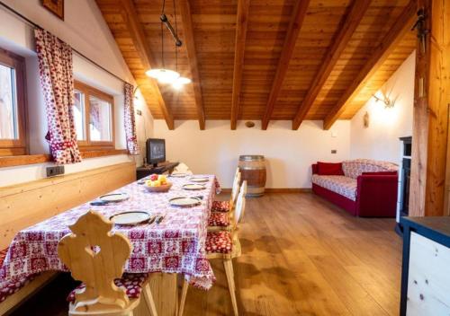 a dining room with a table and a red couch at Baita Stabli-Rifugio Luxury a 1700 mt in Mezzana