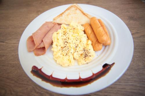 une assiette de nourriture avec des œufs, des saucisses et du pain grillé dans l'établissement The Myth - Sud Sathorn, à Bangkok