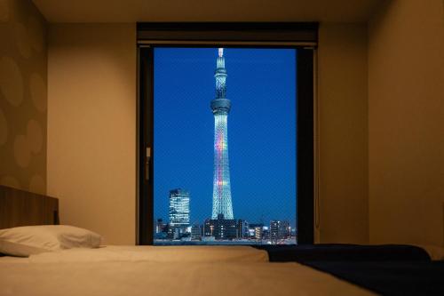 a view of the tokyo tower from a bedroom window at stayme THE HOTEL Asakusa Riverside in Tokyo