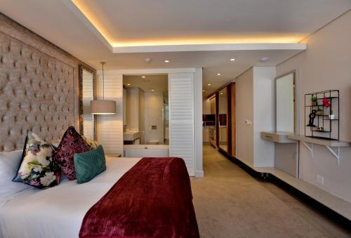 a bedroom with a large bed and a bathroom at Houghton Suites in Johannesburg