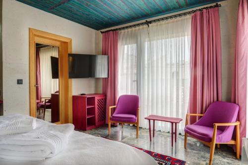 a bedroom with purple chairs and a bed and a tv at Motif Art Cappadocia in Göreme