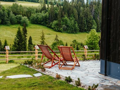 two chairs sitting on a patio in front of a fence at Owczarnia Tatry in Bukowina Tatrzańska