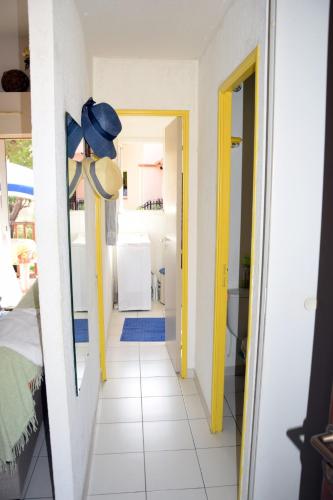 un couloir menant à une salle de bains aux murs jaunes et blancs dans l'établissement Oasis village naturiste, à Leucate