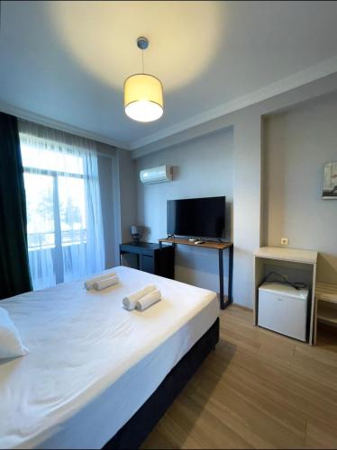 a bedroom with a large white bed and a television at Queen Tamar in Batumi