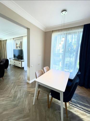 a dining room with a white table and chairs at Queen Tamar in Batumi