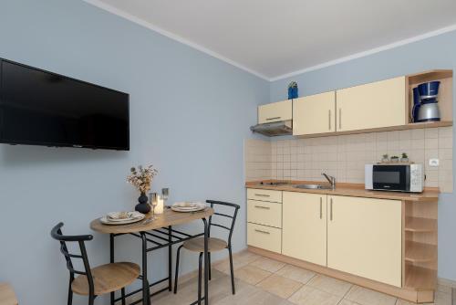 a kitchen with a table with chairs and a tv at Apartamenty przy Promenadzie by Renters in Świnoujście