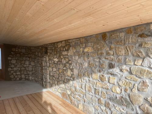 Casa nella natura a Bobbio في بوبيو: جدار حجري في غرفة ذات سقف خشبي