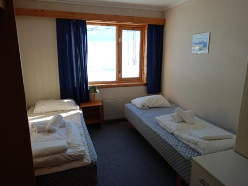 2 Betten in einem Zimmer mit Fenster in der Unterkunft Arctic Lodging North Cape in Skarsvåg