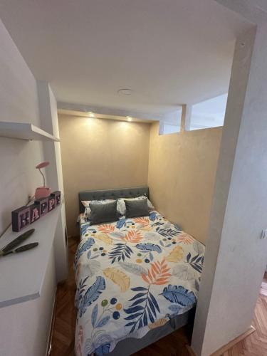 a small bedroom with a bed with a floral bedspread at Apartman Nira in Zenica