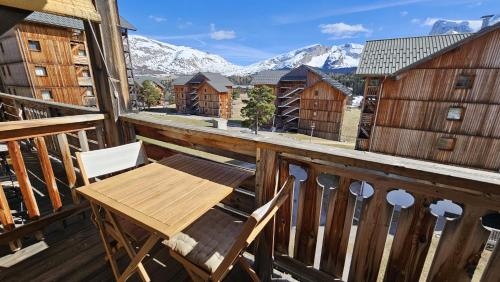 a wooden table and chairs on a balcony with mountains at chalet gentiane cosy T2 labellisé Dévoluy in Superdevoluy