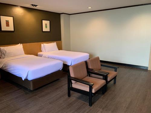 a room with two beds and a chair in it at Bangkok Inter Place in Bangkok
