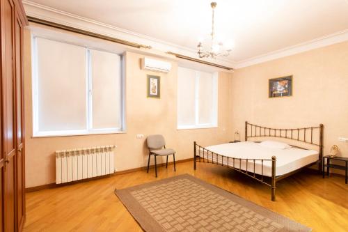 Schlafzimmer mit einem Bett, einem Stuhl und Fenstern in der Unterkunft Suite Penthouse 55 in Tbilisi City